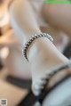 A close up of a woman's foot wearing a diamond bracelet.