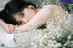 A woman laying on a bed covered in white flowers.