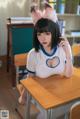 A woman sitting at a desk in a classroom.