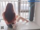 A woman sitting on a window sill looking out a window.