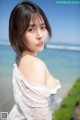 A woman in a white dress standing on a beach.