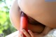 A woman is holding a red dildo in her mouth.