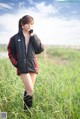 A woman in a black jacket standing in a field.