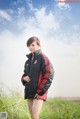 A woman in a black and red jacket standing in a field.