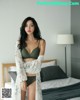 A woman in lingerie standing on a bed in a bedroom.