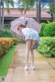 A woman in a skirt and white shirt holding an umbrella.